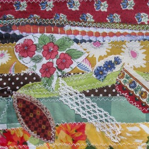 Op de afbeelding: Een kleurrijk patchwork-deken met verschillende stoffen, waaronder bloemenprints, stippen en kant. Het deken is gemaakt van verschillende vormen en maten stof, aan elkaar genaaid met wit garen. Het deken is een uniek en handgemaakt kunstwerk.
