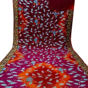 Puede incluir: Un sari de color marrón rojizo y naranja con un patrón floral y ribete dorado. El sari está decorado con lentejuelas y cuentas.