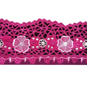 Può includere: Un bordo di pizzo rosa con un bordo a festoni e ricamo floreale bianco. Il pizzo ha un design delicato e intricato con piccole perline argentate.