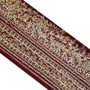 May include: Burgundy velvet trim with gold and silver embroidery. The trim features a repeating pattern of floral and paisley designs.