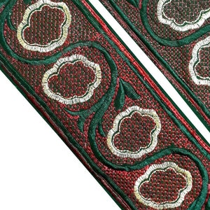 以下が含まれることがあります： 赤と緑の刺繍トリムで、花柄のデザイン。トリムは花に白い輪郭があります。