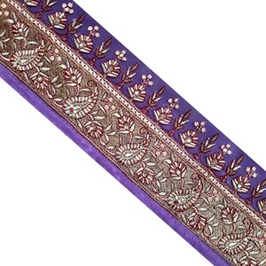 Può includere: Bordino in tessuto viola con ricamo dorato e argentato con motivi floreali e paisley.