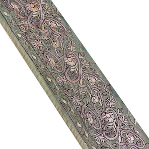May include: A green fabric trim with intricate floral embroidery in pink and white. The trim features a paisley design and is perfect for adding a touch of elegance to any project.