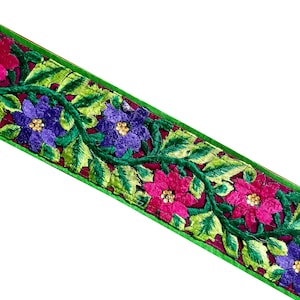 Può includere: Un bordo verde e bordeaux con fiori ricamati in tonalità rosa, viola e verde.