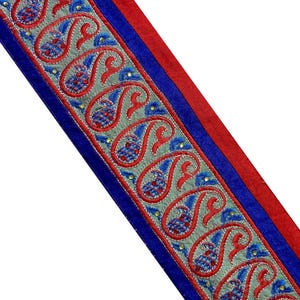 Peut inclure: Garniture rouge et bleue avec un motif paisley argenté. La garniture est brodée de fil argenté et a un dos en velours bleu et rouge.
