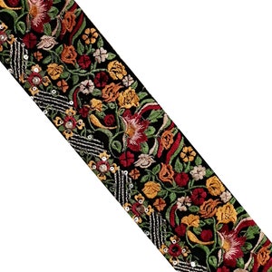Può includere: Bordura ricamata nera con un motivo floreale rosso, giallo e verde. La bordura presenta un motivo ripetuto di fiori e foglie, con paillettes argentate lungo un bordo. Questa bordura decorativa è adatta a vari progetti artigianali.