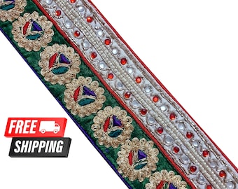 Pode incluir: Bordado verde, vermelho e branco com detalhes dourados e strass. O bordado apresenta um padrão repetitivo de motivos florais.