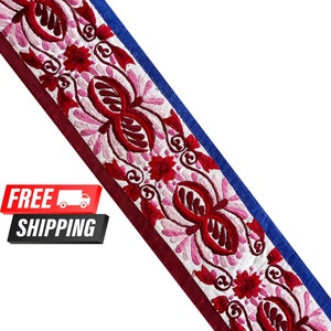 Può includere: Finitura ricamata rossa e rosa su sfondo bianco con bordatura blu. La finitura ha un motivo floreale.