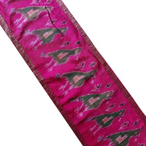 Puede incluir: Borde de tela rosa con un patrón ikat verde y blanco y un borde burdeos.