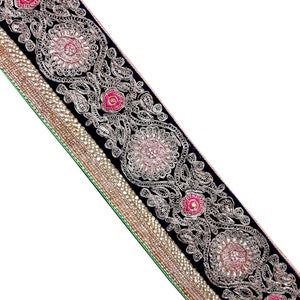 Può includere: Passamaneria in velluto nero con ricamo argento e rosa. La passamaneria presenta un motivo floreale ripetuto e paillettes.