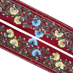 May include: Red fabric trim with embroidered floral designs in yellow, blue, and green. The trim has a beaded border.