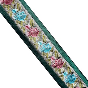 Può includere: Nastrino di velluto verde con un motivo floreale argento e bianco. I fiori sono ricamati in rosa, blu e verde.