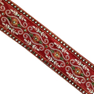 May include: Red velvet trim with silver and gold embroidery, featuring a floral design and small round mirrors.
