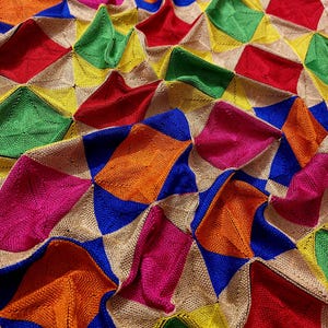 Puede incluir: Una tela colorida con un patrón geométrico de cuadrados y triángulos. La tela está hecha de un material tejido y tiene una superficie texturizada. Los colores son brillantes y vibrantes, incluyendo rojo, naranja, amarillo, verde, azul y rosa.