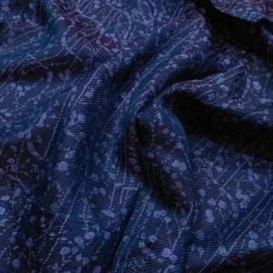 Può includere: Primo piano di un tessuto blu con un motivo floreale. Il tessuto è stropicciato e ha una texture morbida e setosa.