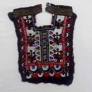 Puede incluir: Un cuello bordado colorido con intrincados patrones en rojo, verde, azul y blanco. El cuello está hecho de tela negra y tiene un borde con flecos.