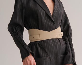 May include: A black and white striped blazer with a beige leather belt. The belt has a pointed front and a buckle with gold accents.