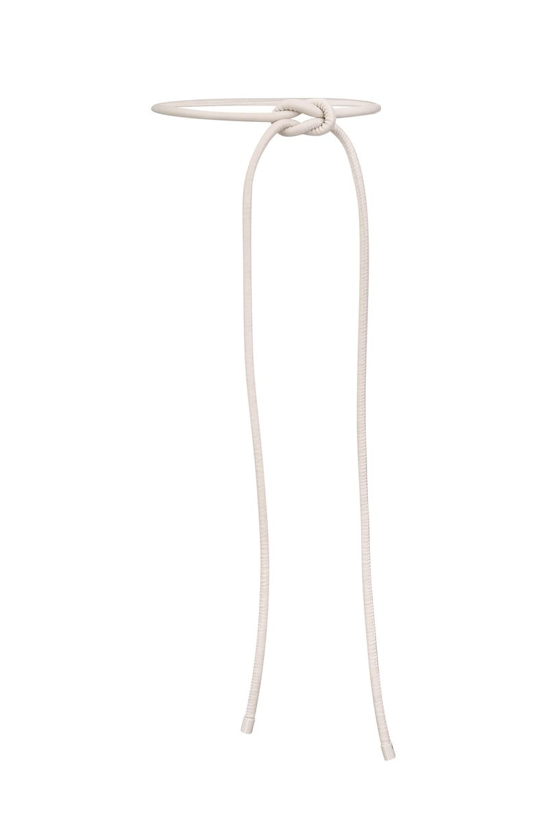 May include: A cream-colored belt with a knotted design. The belt features a circular band connected to two long, thin cords. The cords hang down from the knot, creating a simple yet elegant accessory.