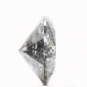 May include: A clear, faceted diamond with a round shape. The diamond is set in a silver setting.