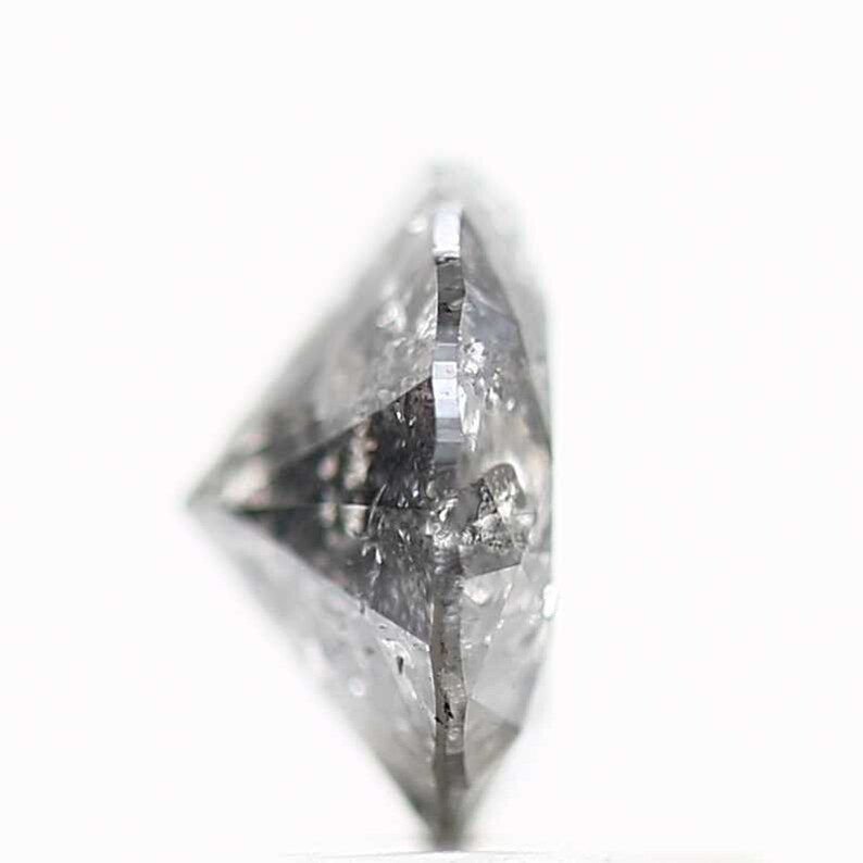 May include: A clear, faceted diamond with a round shape. The diamond is set in a silver setting.