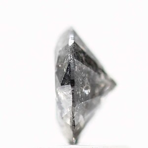 May include: A close-up side view of a clear, faceted, gray diamond gemstone.