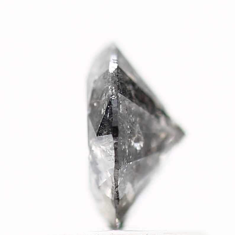 May include: A close-up side view of a clear, faceted, gray diamond gemstone.