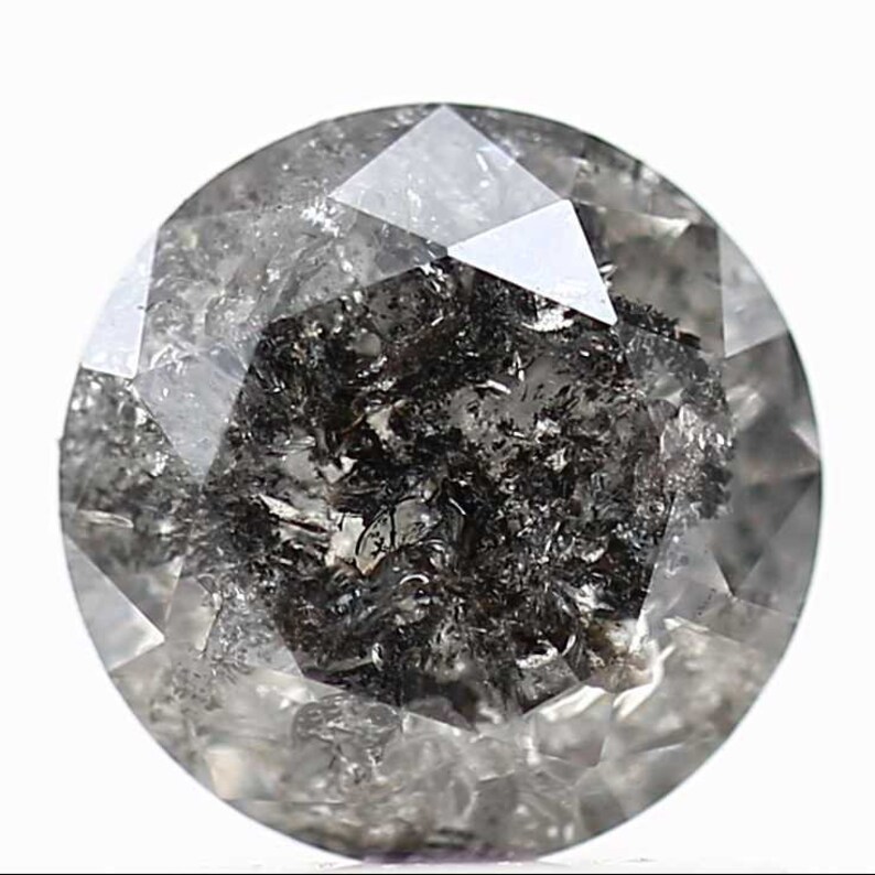 May include: A round, faceted, black diamond with inclusions. The diamond is cut in a round brilliant style.