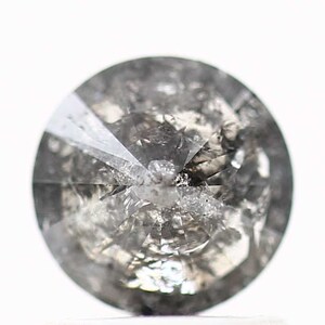 May include: A round, gray diamond with a faceted cut. The diamond has many inclusions and is not clear.