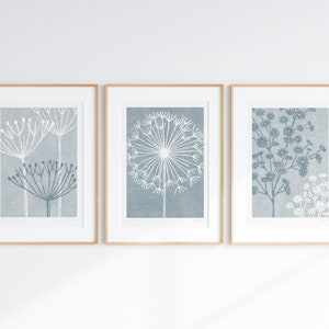 May include: Three framed prints of stylized blue and white floral illustrations. The prints are in simple wooden frames and are hung on a white wall.