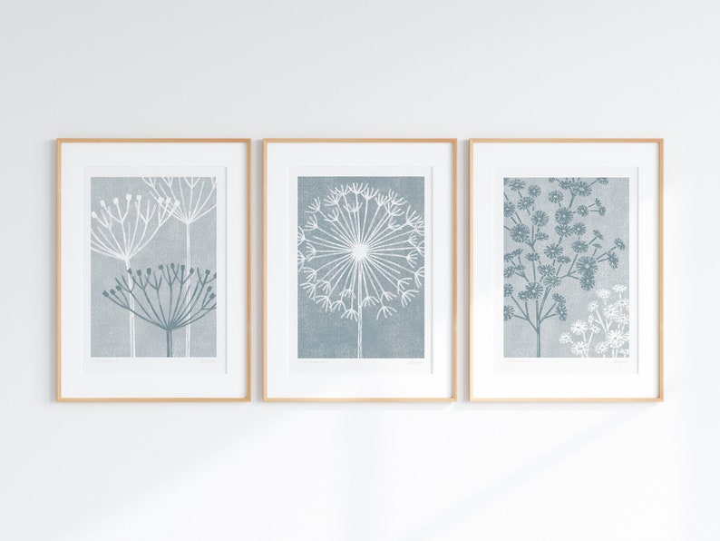 May include: Three framed prints of stylized blue and white floral illustrations. The prints are in simple wooden frames and are hung on a white wall.