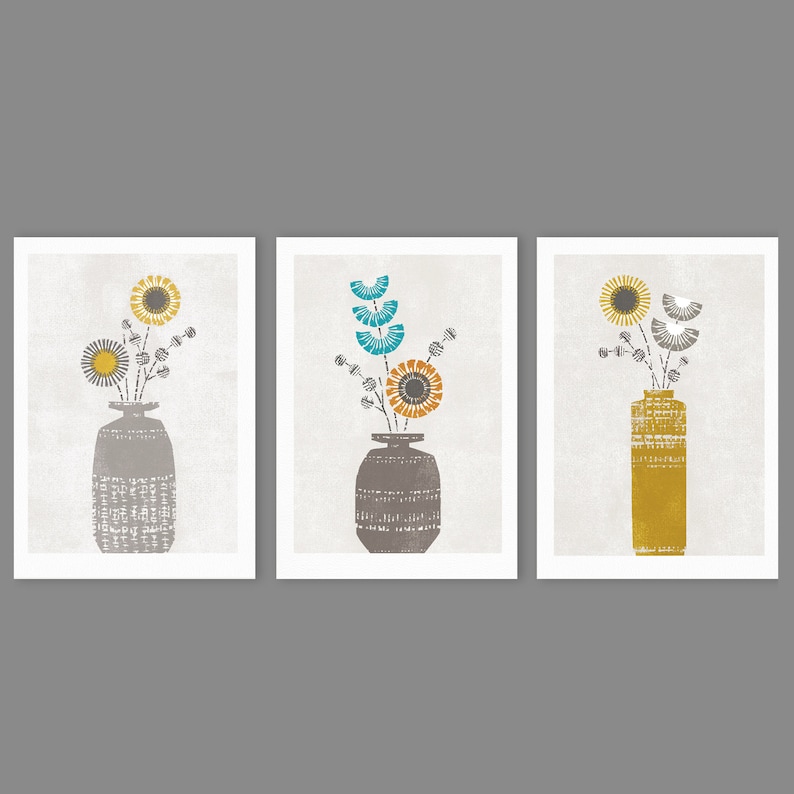 May include: Three framed prints with a minimalist design featuring stylized floral arrangements in gray, yellow, and blue hues. Each print depicts a different floral arrangement in a gray or yellow vase.