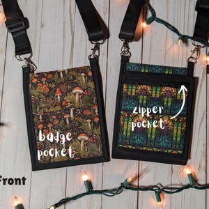 Könnte beinhalten: Zwei kleine, schwarze Umhängetaschen mit verstellbaren Trägern. Eine Tasche hat einen Pilz- und Wald-Print, beschriftet mit "badge pocket". Die andere hat ein Buntglas-Design und ein "zipper pocket"-Etikett. Beide liegen auf einer hellen Holzoberfläche.