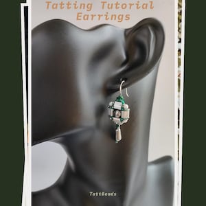 Può includere: Primo piano di un orecchino a chiacchierino su una testa di manichino nera. L'orecchino presenta un design geometrico con perline argentate, bianche e verdi e una perlina pendente a forma di goccia. Il testo "Tatting Tutorial Earrings" è in alto.