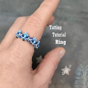 Pode incluir: Um anel de tatting azul e prateado com um design de contas. O anel está em um dedo e o texto "Tatting Tutorial Ring" é visível no fundo.