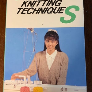 May include: A VHS video tape titled "General Knitting Technique" featuring a woman in a beige sweater using a knitting machine. The woman is smiling and looking at the camera. The machine is white and has two spools of yarn, one pink and one yellow.