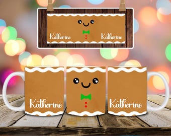 May include: Three white ceramic mugs with a gingerbread man design. The mugs are brown with a white scalloped edge and feature a smiling face, green bow tie, and the name "Katherine". A matching sign hangs above.