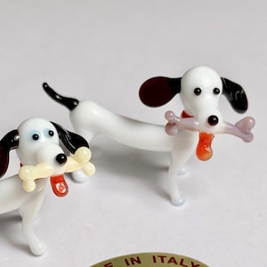 Black and white puppies with a bone and their tongue out. Murano glass animal figurine made in Venice