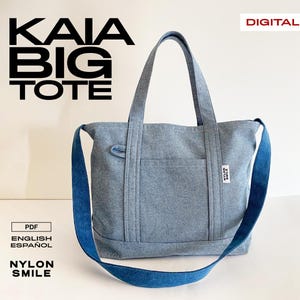 May include: A grey denim tote bag with a blue shoulder strap. The bag features the text "KAIA BIG TOTE". Additional text includes "DIGITAL", "PDF", "ENGLISH ESPAÑOL", and "NYLON SMILE".