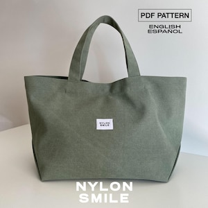 May include: A sage green tote bag with two top handles and a small white rectangular label centered on the front featuring the black text NYLON SMILE. The image includes the text PDF PATTERN ENGLISH ESPAÑOL at the top and NYLON SMILE at the bottom.
