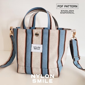 May include: A tote bag featuring vertical stripes in light blue, dark brown, and off-white. The bag has two top handles, a detachable shoulder strap, a metal snap closure, and a white label with the text NYLON SMILE. Text reads PDF PATTERN.