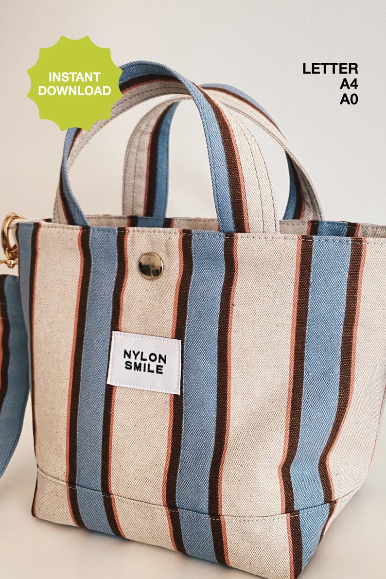 May include: A tote bag featuring vertical stripes in light blue, dark brown, and cream. The bag has two top handles, a silver snap button closure, and a white rectangular label with the black text NYLON SMILE. Text in the image reads INSTANT DOWNLOAD, LETTER, A4, A0.