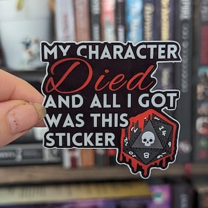 May include: A black and red sticker with a white skull and dice graphic. The sticker says "My character died and all I got was this sticker."
