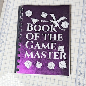 May include: A purple book with a glittery cover and the title "Book of the Game Master". The cover features a dragon and several dice.