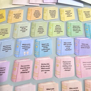 Peut inclure: Cartes en forme de livre de couleurs pastel vari&eacute;es avec des questions sur les livres. Chaque carte contient une question diff&eacute;rente, comme &laquo;&nbsp;Ce livre vous a-t-il donn&eacute; une gueule de bois ou un c&acirc;lin&nbsp;?&nbsp;&raquo; et &laquo;&nbsp;Quelle a &eacute;t&eacute; votre premi&egrave;re impression du personnage principal&nbsp;?&nbsp;&raquo;