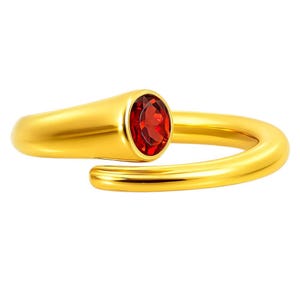 May include: A gold-colored ring with a vibrant red oval-shaped gemstone. The ring has a smooth, polished finish and a modern, minimalist design. The gemstone is set in a bezel setting, adding to the ring's elegant appearance. A piece of jewelry.