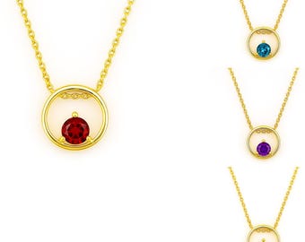 May include: Gold-toned necklaces with a circular pendant design. Each necklace features a different colored gemstone: red, blue, purple, and white. The gemstones are set within a gold circle, suspended from a delicate chain.