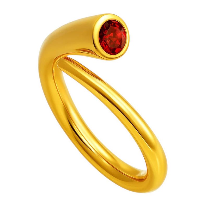 May include: A gold-colored ring with a curved design. The ring features a vibrant red gemstone set in a cylindrical end. The band curves around to meet the gemstone setting, creating a unique and modern look.