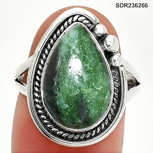 May include: A silver ring featuring a pear-shaped green stone with dark green and black inclusions. The stone is set in a decorative bezel with a twisted rope design. The ring has a simple band and three small silver beads on the side. The text "SDR236266" is visible.