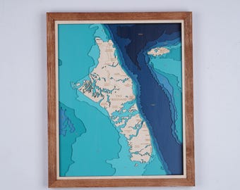 May include: A framed wooden map of The Bahamas, featuring a layered design with varying shades of blue and tan. The map shows the islands and surrounding ocean depths, with the text "THE BAHAMAS" visible.