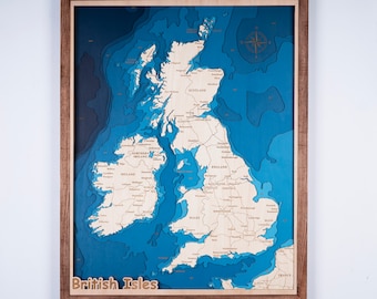 May include: A wooden 3D map of the British Isles with a blue ocean background. The map is framed in a brown wood frame and includes the text "British Isles".